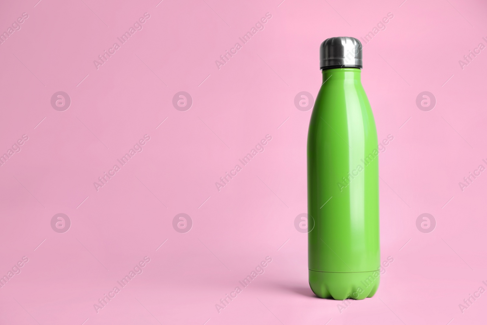 Photo of Stylish thermo bottle on pink background, space for text