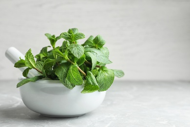 Photo of Mortar with fresh green mint and pestle on table. Space for text