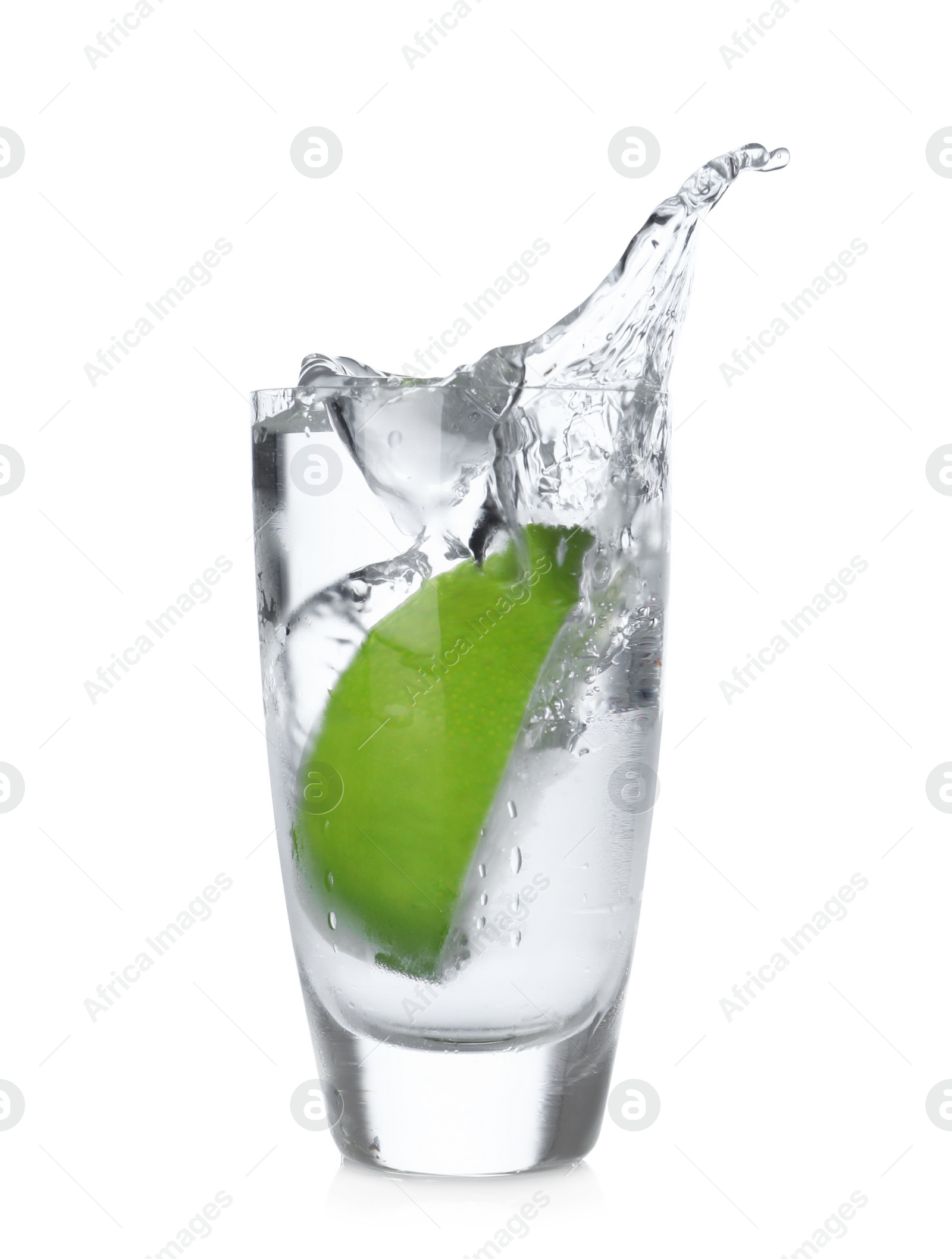 Photo of Lime slice falling into shot glass of vodka on white background