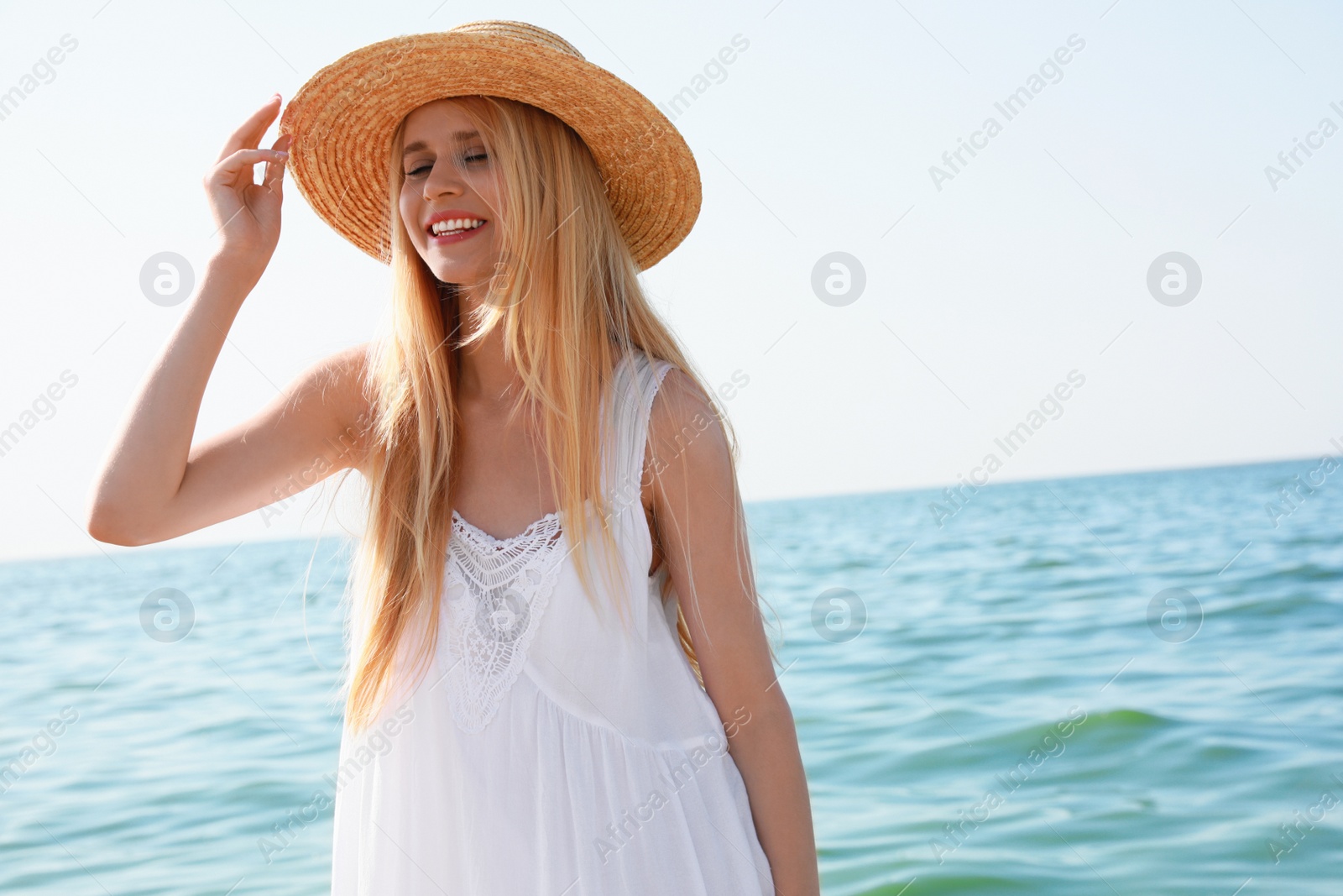 Photo of Beautiful young woman with straw hat near sea on sunny day in summer