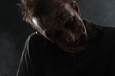 Photo of Scary zombie on dark background, closeup. Halloween monster