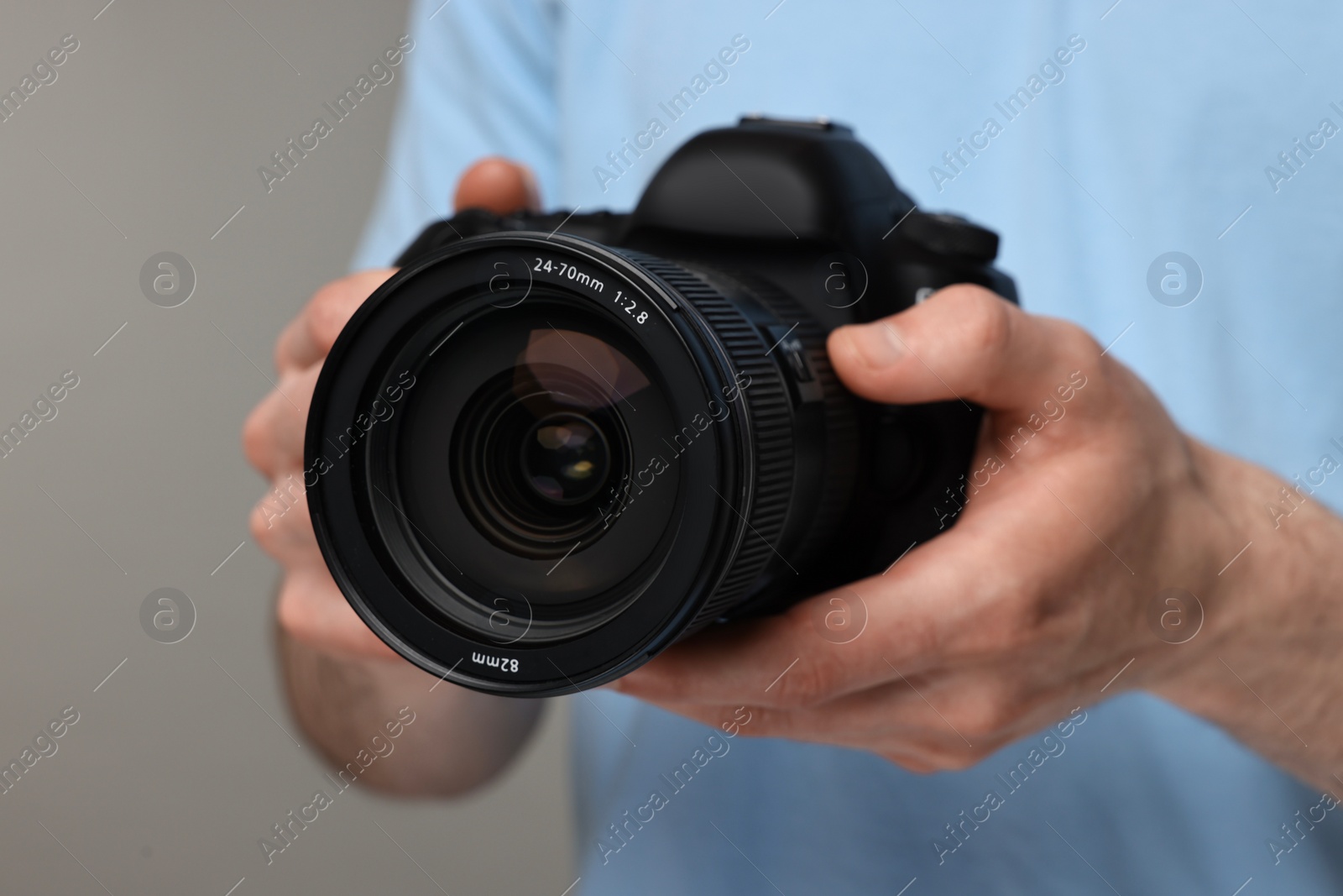 Photo of Photographer holding camera on grey background, closeup