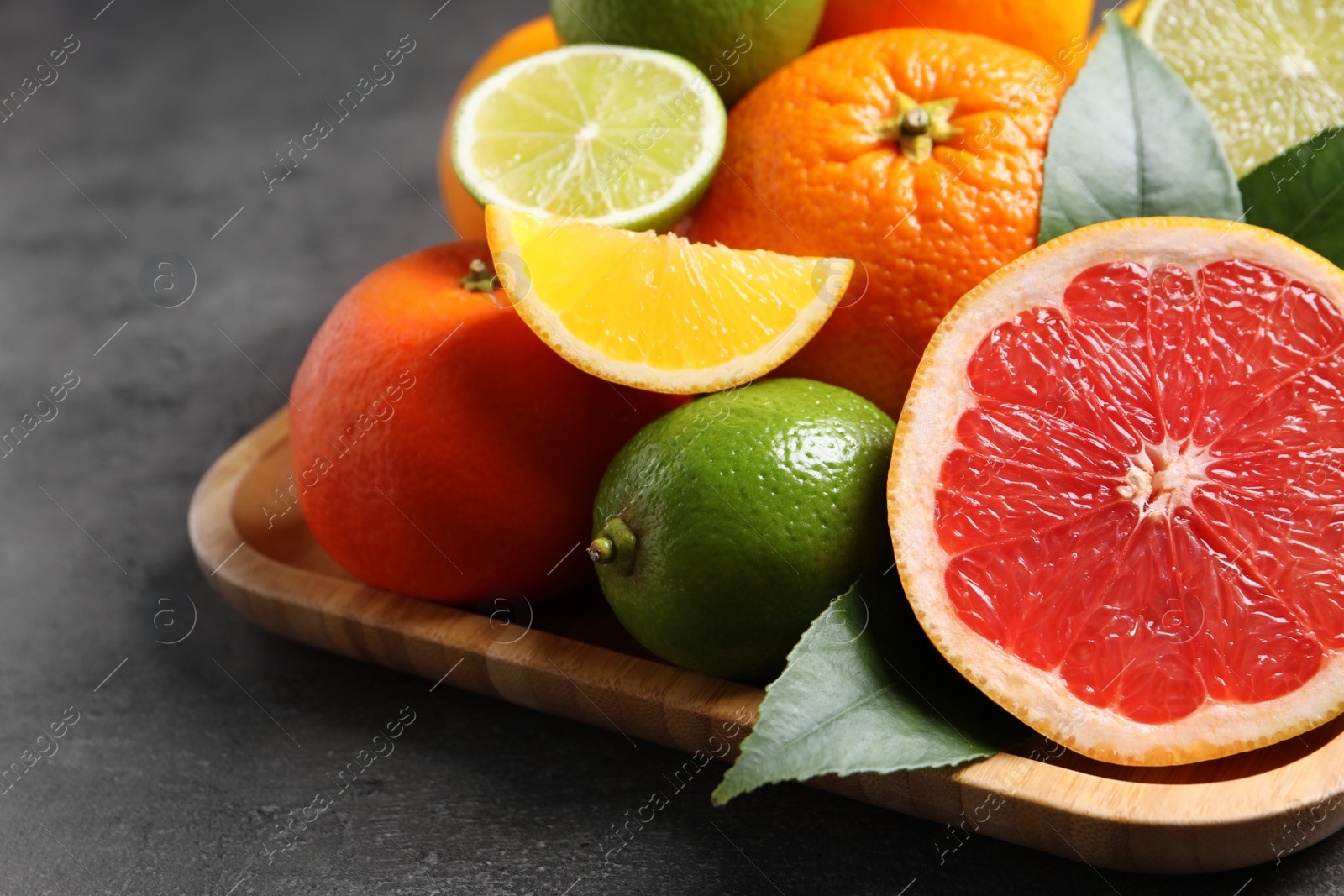 Photo of Different citrus fruits on black table, closeup