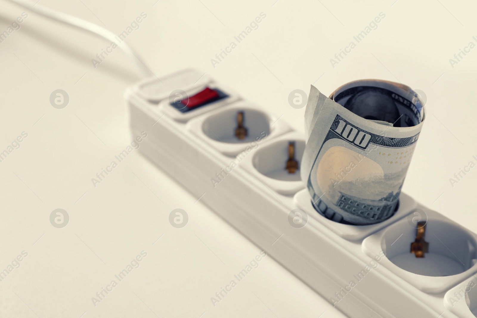 Photo of Extension board with rolled dollar banknotes on white table, closeup