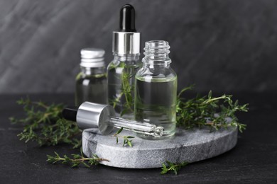 Photo of Natural thyme essential oil on black table