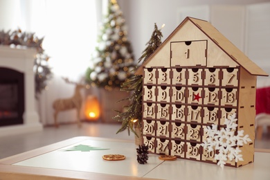 Wooden house shaped Advent calendar in room decorated for New Year