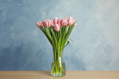 Beautiful pink spring tulips in vase on wooden table