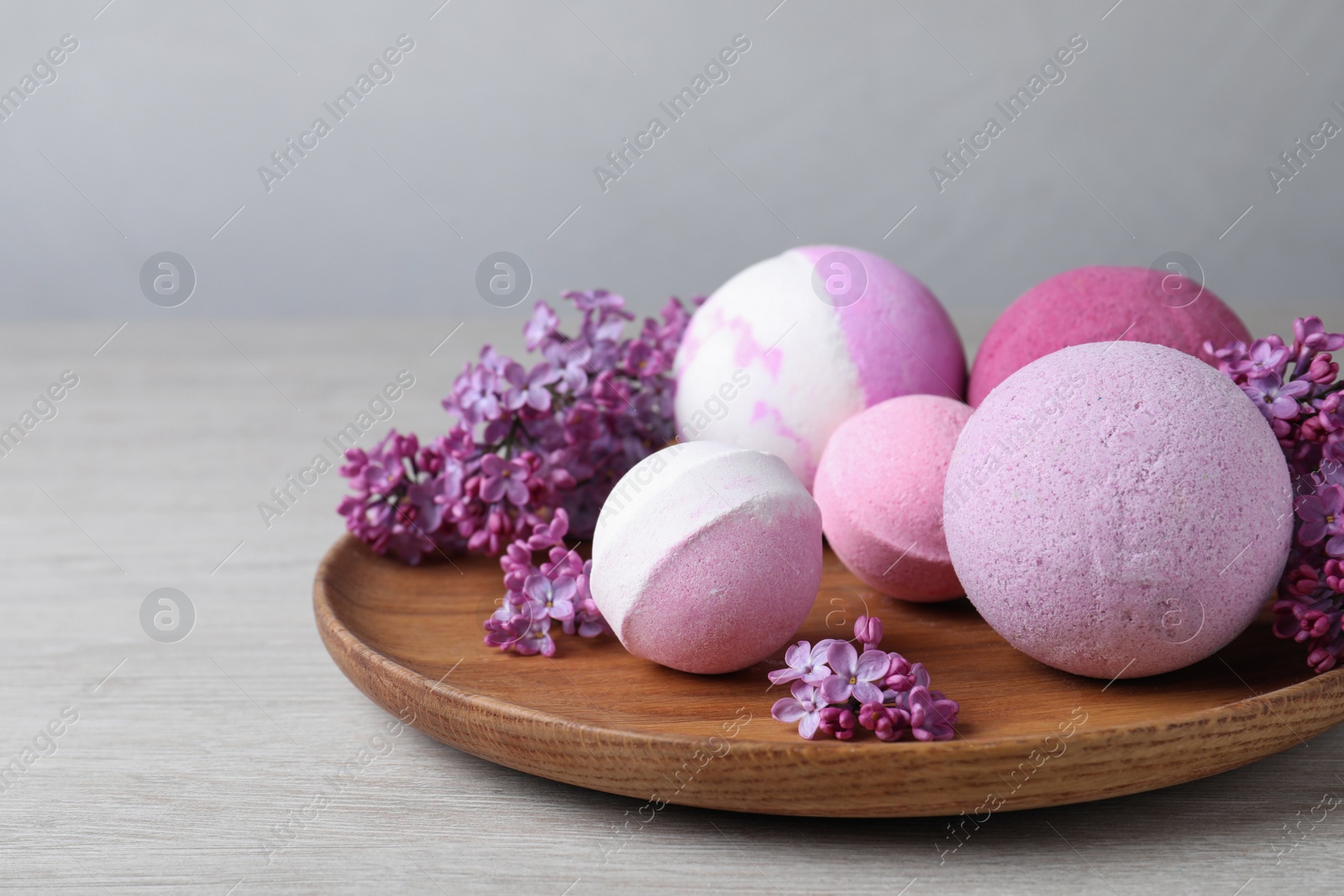 Photo of Fragrant bath bombs and lilac flowers on wooden table, space for text