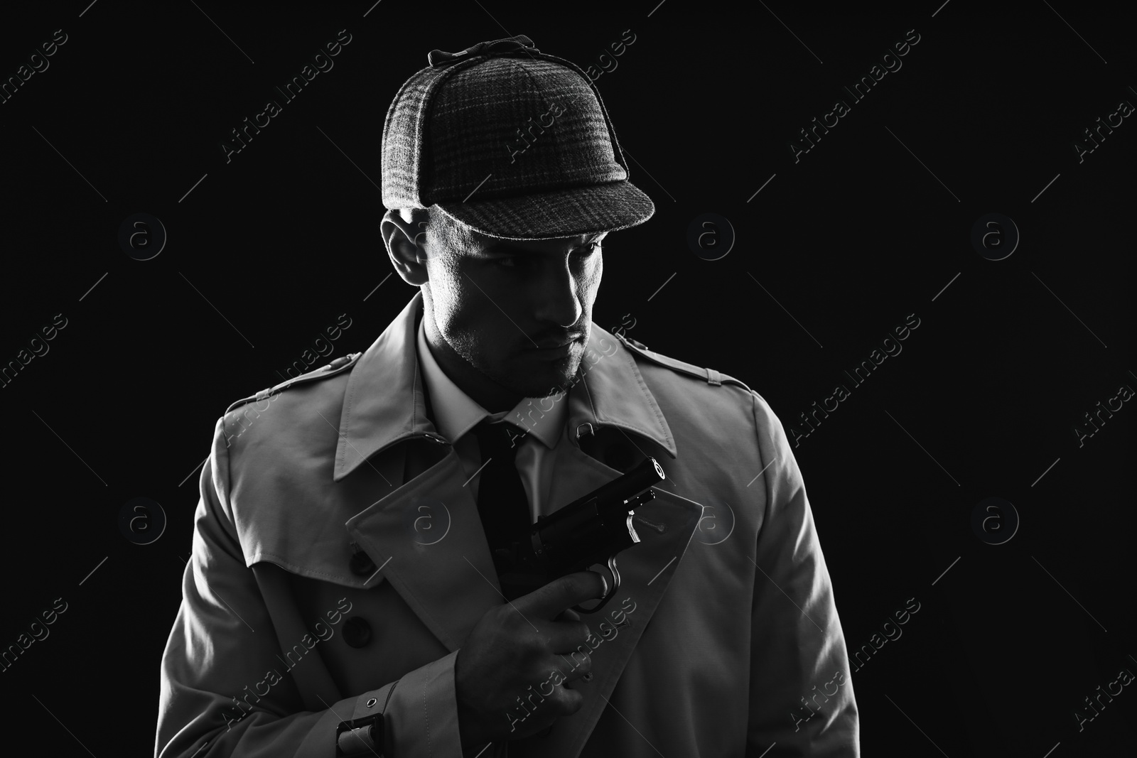 Photo of Old fashioned detective with revolver on dark background, black and white effect