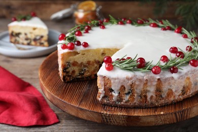 Traditional Christmas cake decorated with rosemary and cranberries on table, closeup