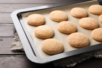 Photo of Baking sheet with delicious sugar cookies on wooden table, closeup