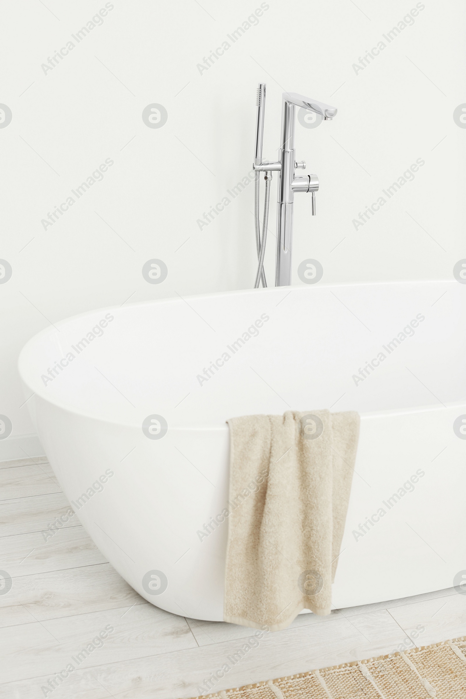 Photo of Beautiful white tub with towel in bathroom. Interior design