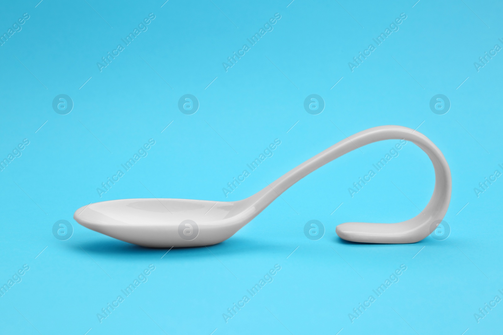 Photo of Clean empty ceramic appetizer spoon on blue background