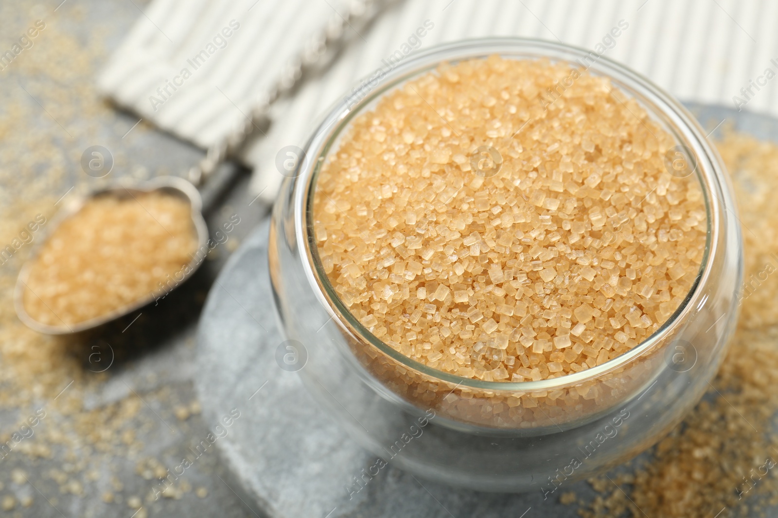 Photo of Brown sugar in bowl on grey table, closeup