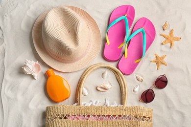 Photo of Different beach accessories on sand, flat lay