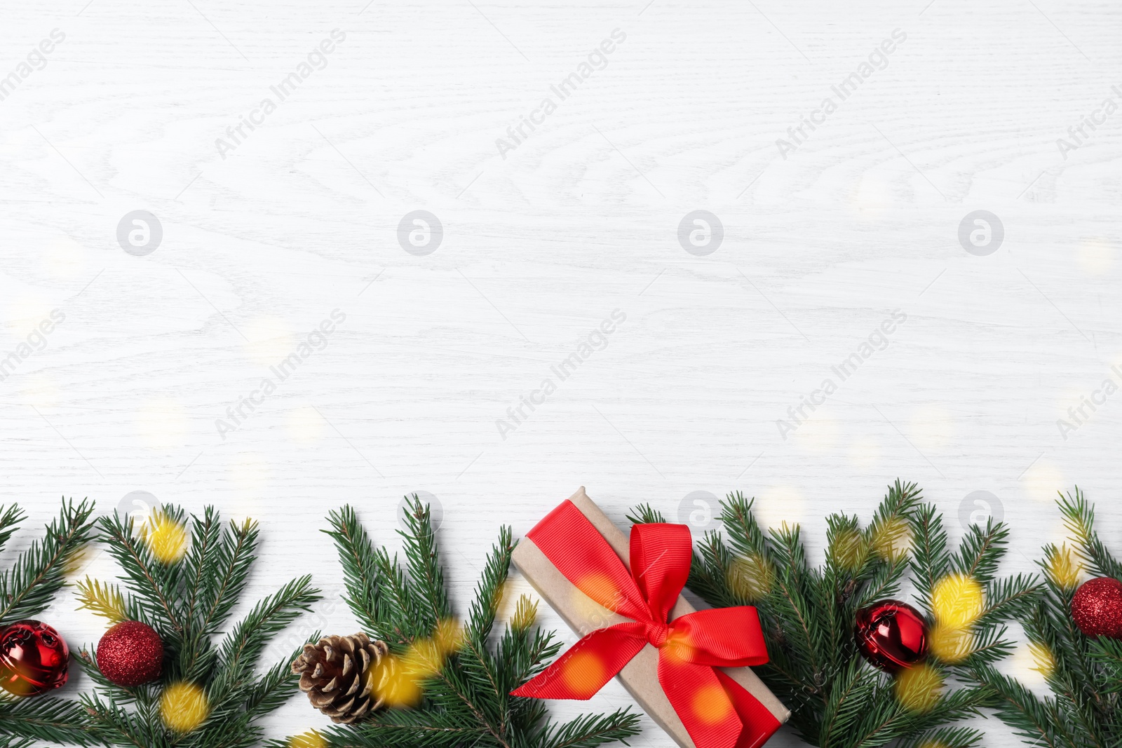 Photo of Christmas greeting card with space for text. Flat lay composition of fir tree branches and festive decor on white wooden background