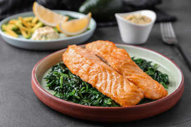 Photo of Tasty salmon with spinach on grey table