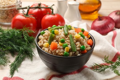 Photo of Delicious pearl barley with vegetables and other products on table, closeup