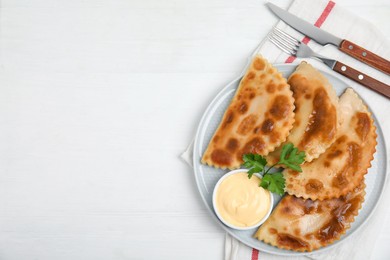 Photo of Delicious fried chebureki with sauce served on white table, top view. Space for text