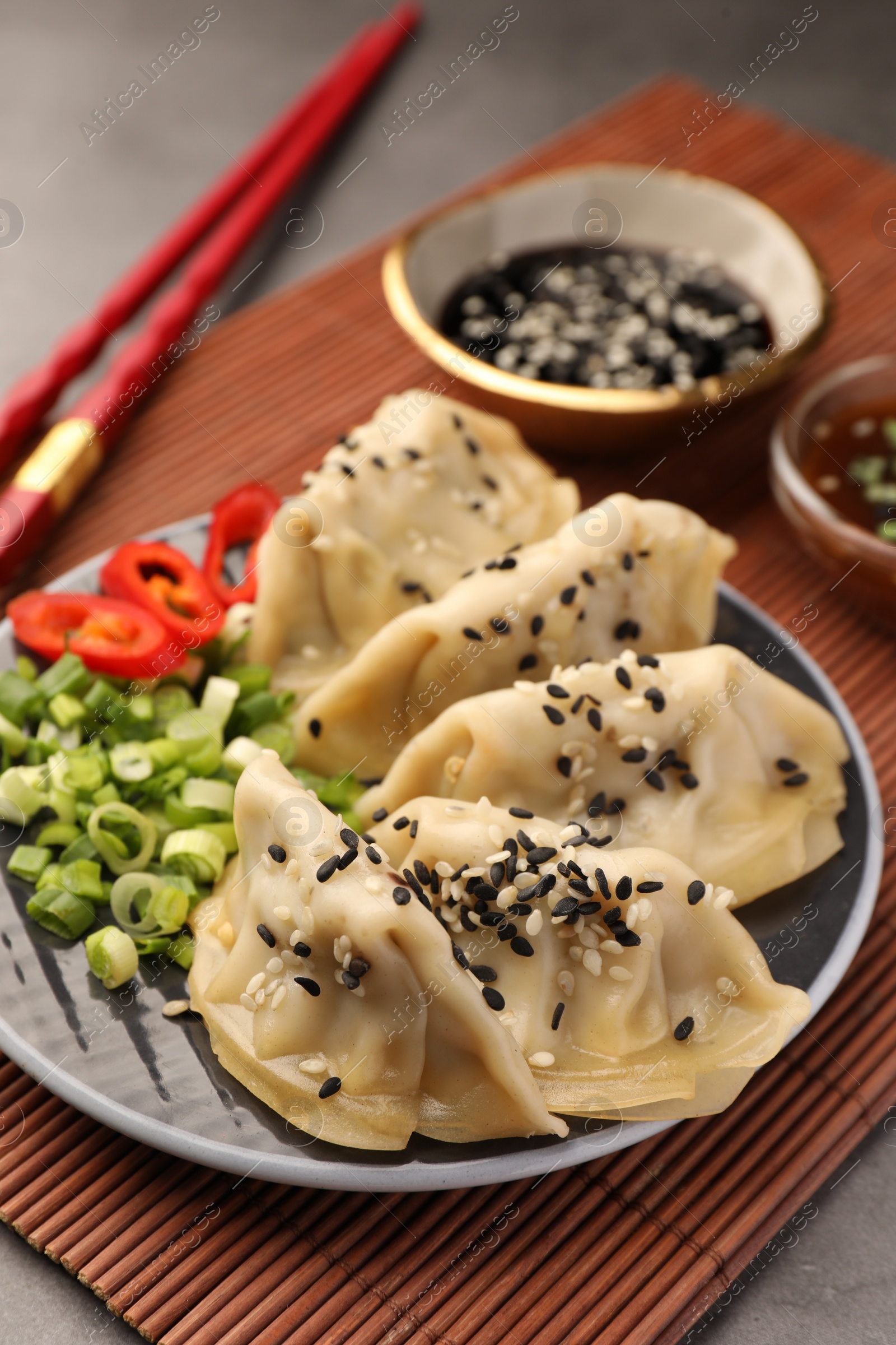 Photo of Delicious gyoza (asian dumplings) with sesame seeds and green onions on table
