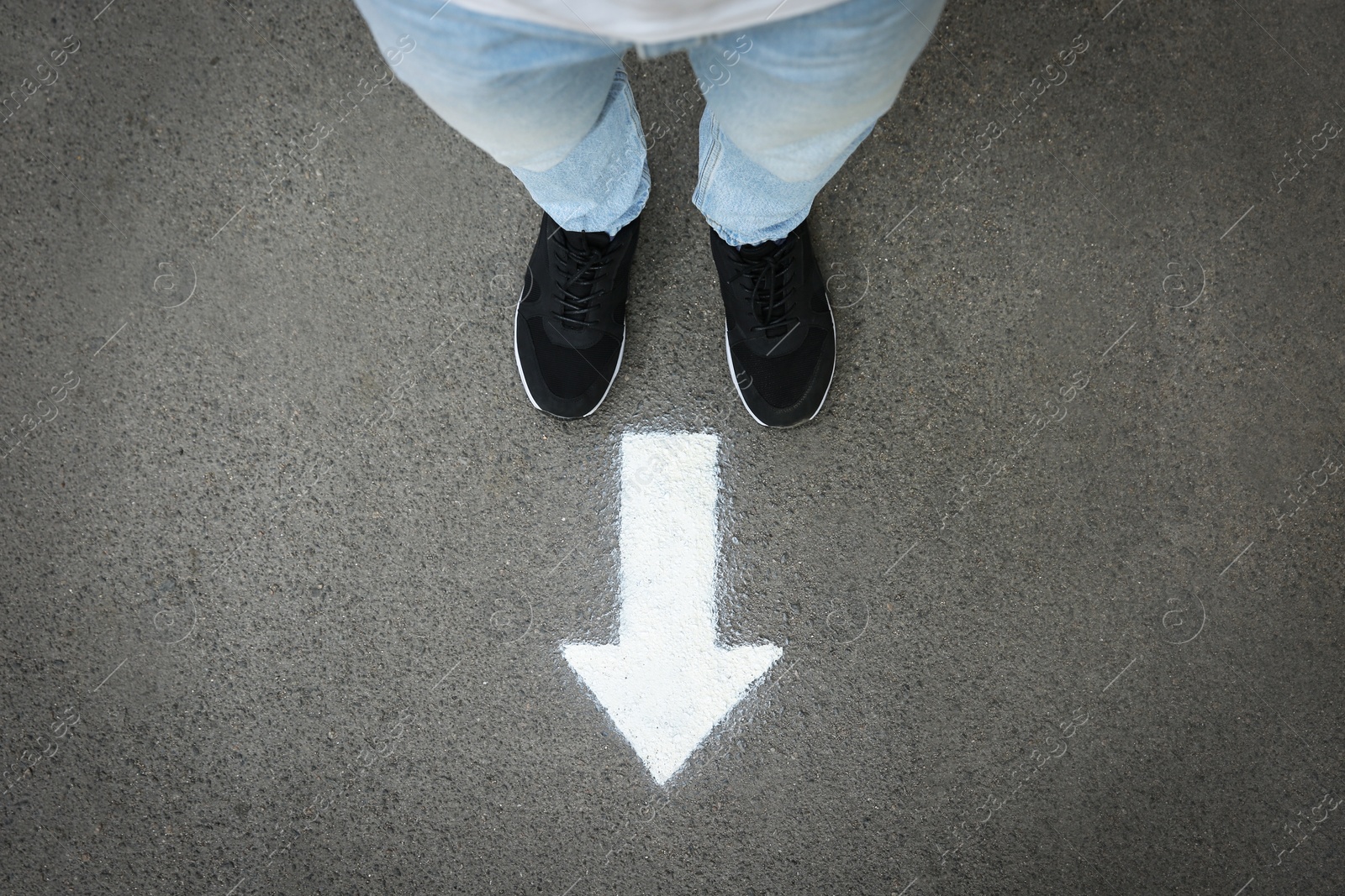 Photo of Man standing near arrow on asphalt, top view