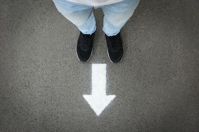 Photo of Man standing near arrow on asphalt, top view