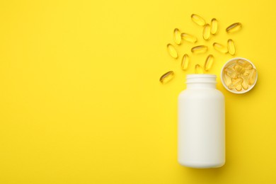 Photo of Softgel capsules, lid and bottle on yellow background, flat lay. Space for text