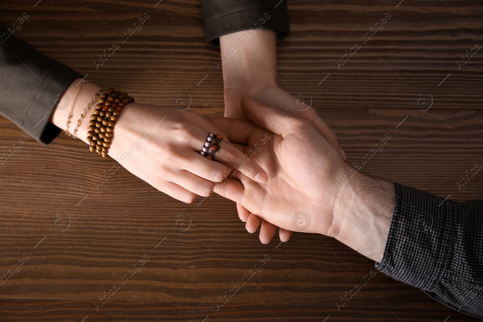 Photo of Chiromancer reading lines on man's palm at table, above view