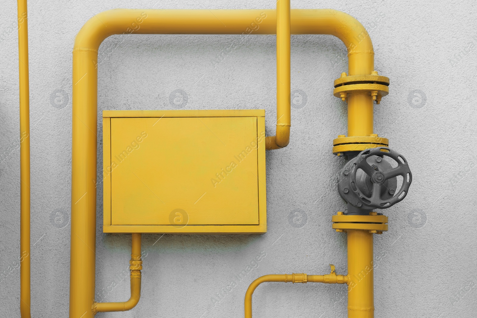 Photo of Gas meter box and pipes near grey wall outdoors