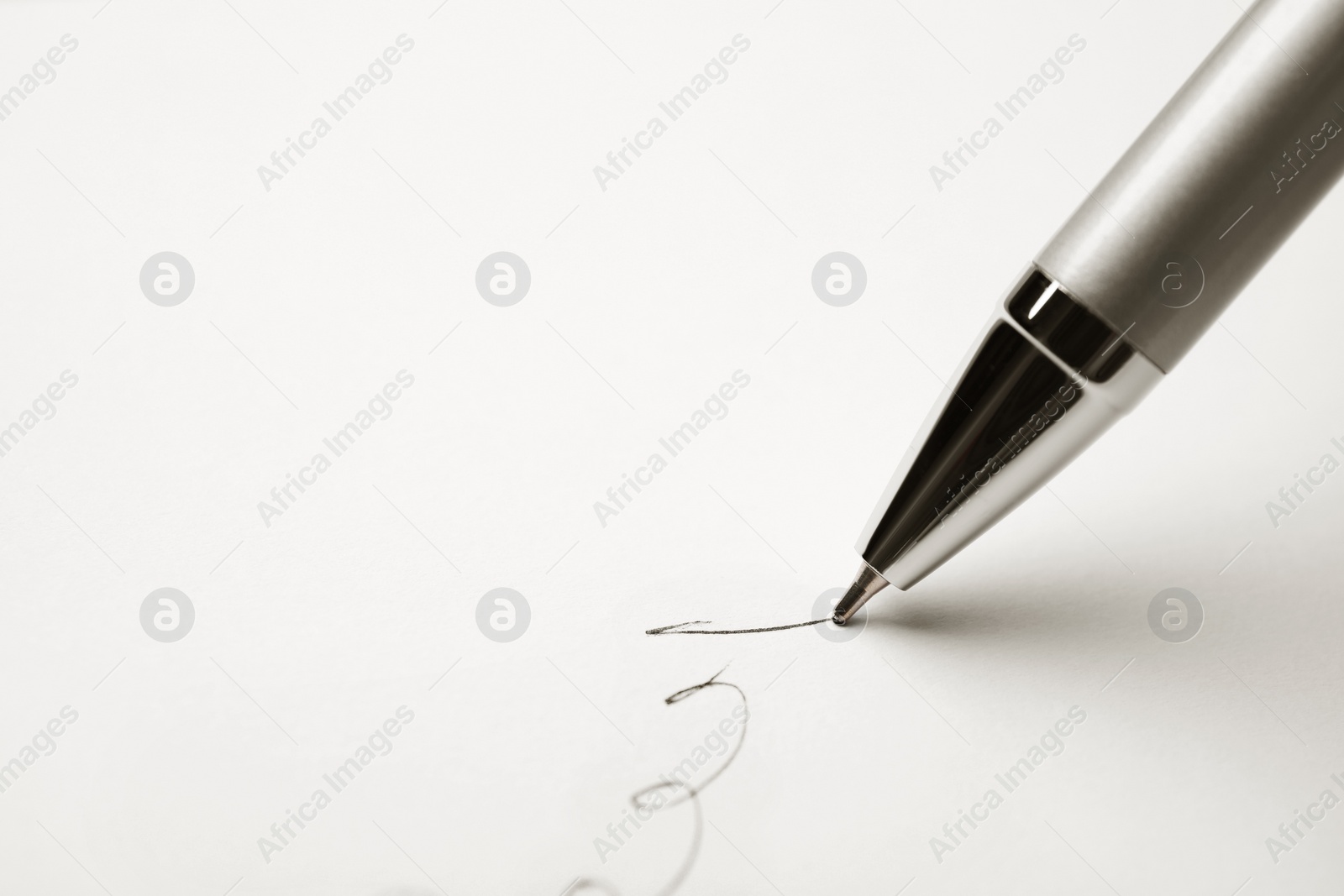 Photo of Signing on sheet of white paper with pen, closeup