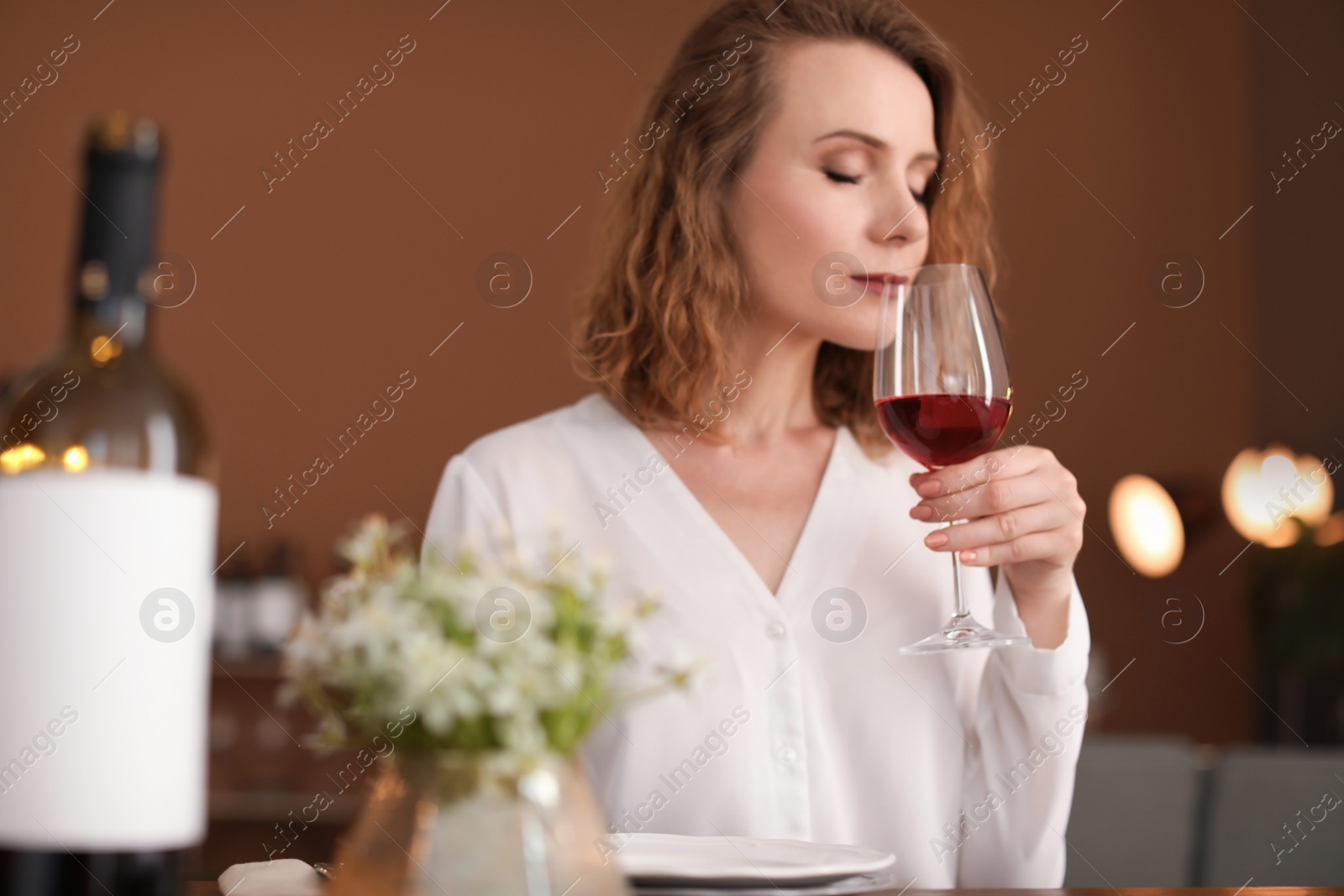 Photo of Woman with glass of wine at table in restaurant