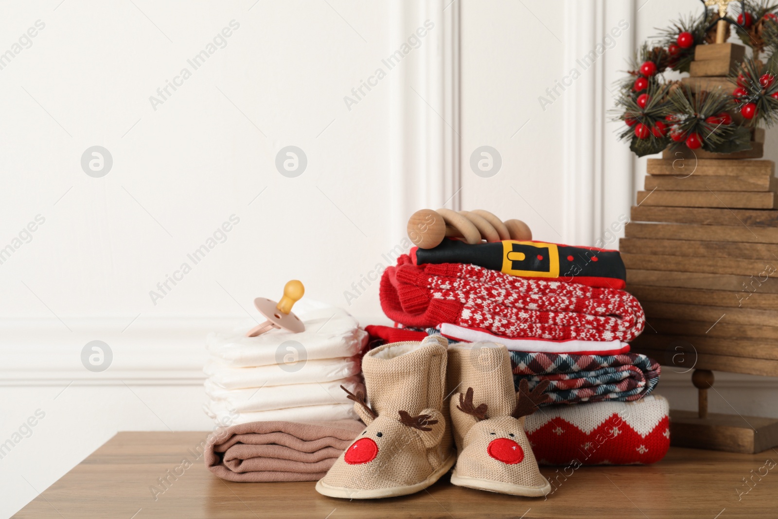 Photo of Baby clothes, accessories and Christmas decor on wooden table