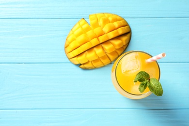 Photo of Fresh mango drink and cut fruit on blue wooden table, top view. Space for text