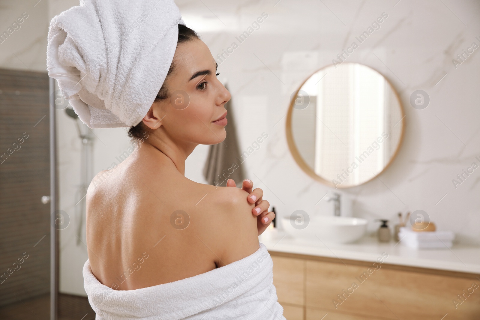 Photo of Beautiful young woman with towel on head in bathroom