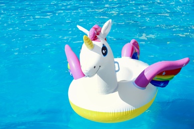 Photo of Funny inflatable unicorn ring floating in swimming pool on sunny day