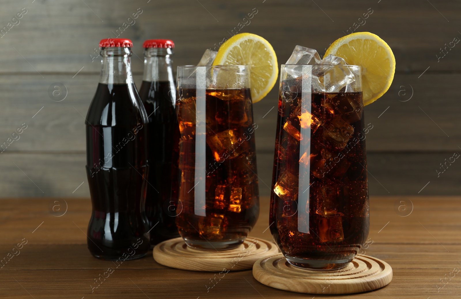 Photo of Bottles and glasses of refreshing soda water on wooden table