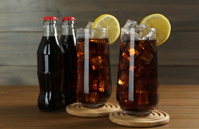 Photo of Bottles and glasses of refreshing soda water on wooden table