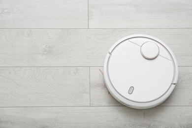 Hoovering floor with modern robotic vacuum cleaner indoors, top view. Space for text