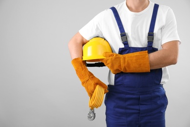 Photo of Male industrial worker in uniform on light background, closeup with space for text. Safety equipment