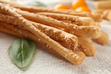 Photo of Delicious grissini sticks, basil leaf and yellow tomatoes on tablecloth, closeup