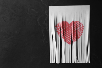 Photo of Top view of cut paper with heart drawing on black stone background, space for text. Relationship problems concept