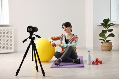 Happy sports blogger recording fitness lesson with camera at home