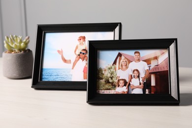Photo of Frames with family photos and houseplant on white wooden table