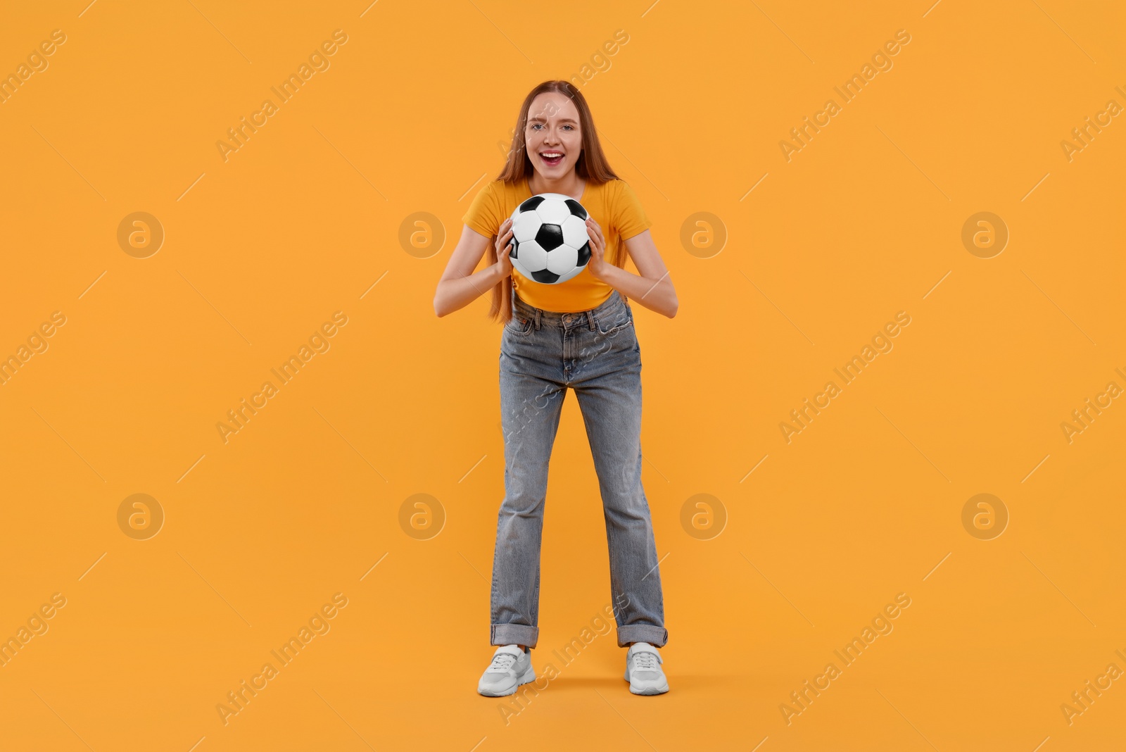 Photo of Emotional sports fan with ball on yellow background