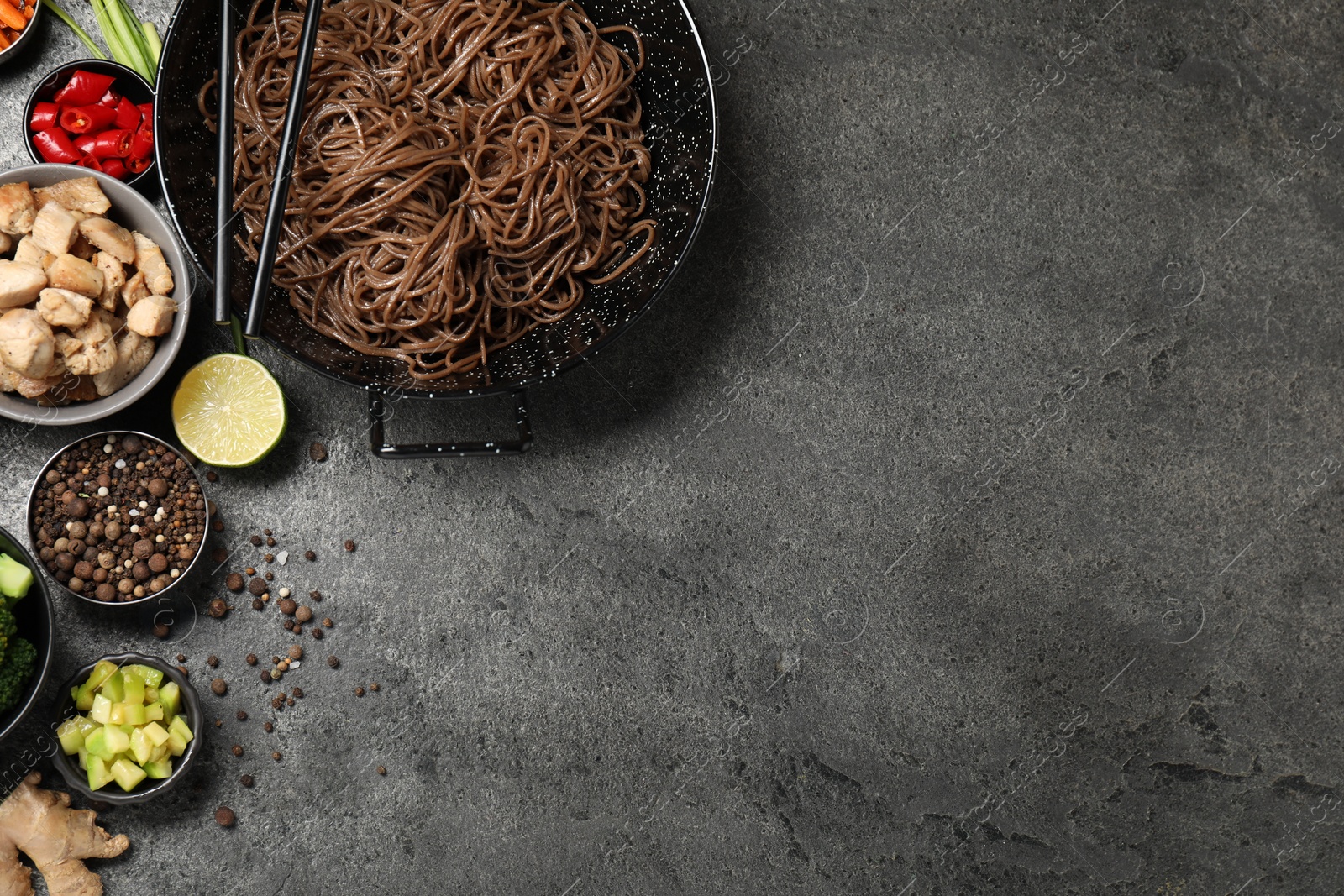 Photo of Wok with noodles, chicken and other products on grey table, flat lay. Space for text