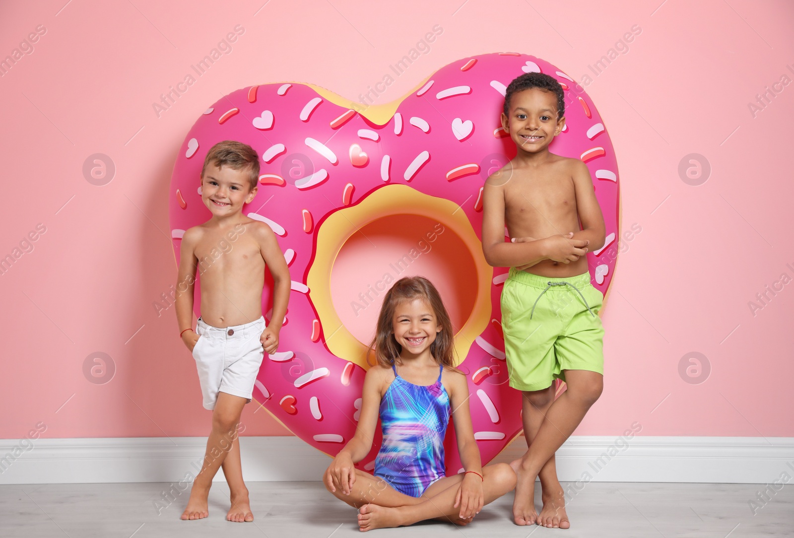 Photo of Cute little children with bright heart shaped inflatable ring near color wall