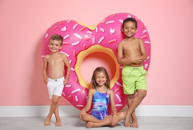 Photo of Cute little children with bright heart shaped inflatable ring near color wall