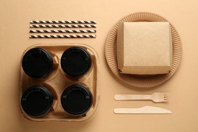 Photo of Paper and wooden tableware on beige background, flat lay. Eco friendly lifestyle