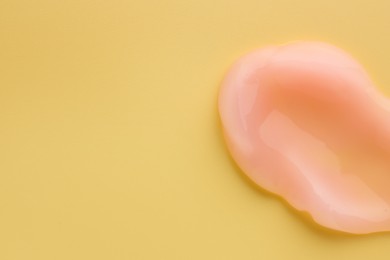 Photo of Sample of face cream on yellow background, top view. Space for text
