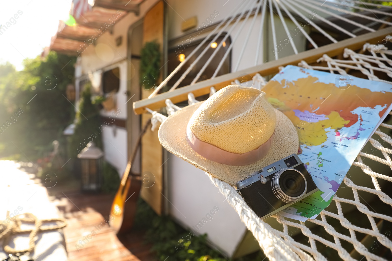 Photo of Comfortable hammock with hat, world map and vintage camera near motorhome outdoors on sunny day